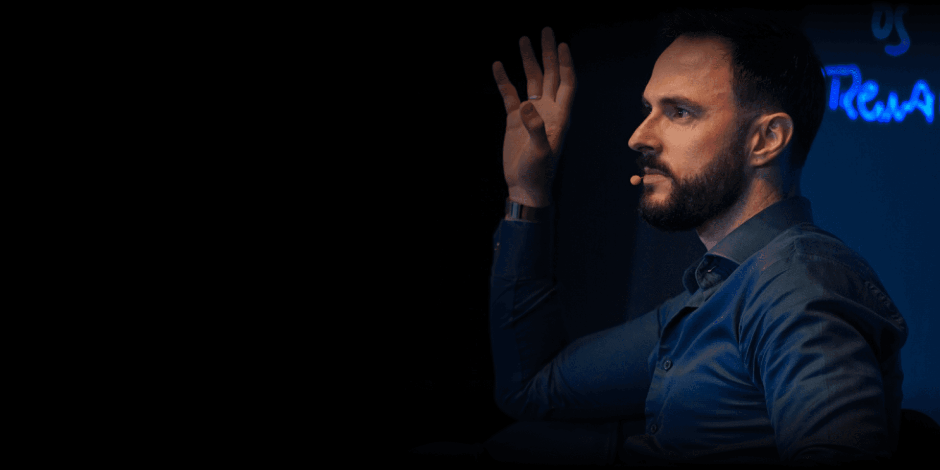 Jônas Pastore de perfil, com microfone, gesticulando durante uma palestra